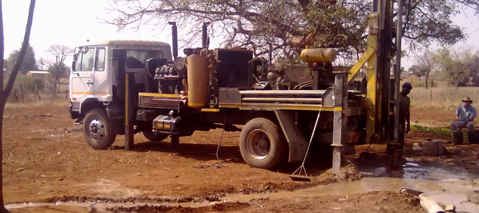 Bona Manzi rig drilling on a farm with water flowing from the site